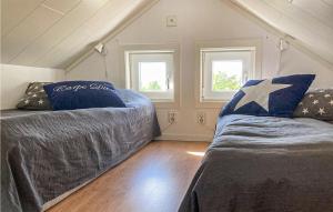 a attic bedroom with two beds and two windows at 2 Bedroom Lovely Apartment In Lysekil in Lysekil