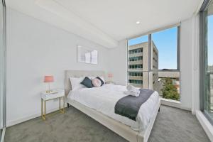 a white bedroom with a bed and a window at Aircabin｜Mascot｜Spacious & Modern｜Walk to station in Sydney