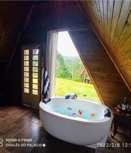 a large bath tub in a room with a window at Chalés do Palácio in Campos do Jordão