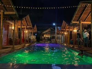 dos personas de pie en una piscina por la noche en The Bangka Beach Guesthouse en Siquijor