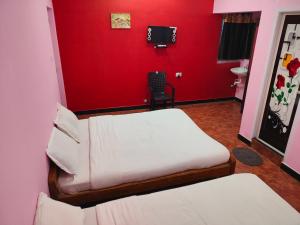 a room with two beds and a red wall at smile stone individual cottage in Ooty