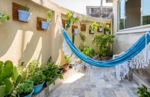 un patio avec des plantes en pot et un hamac bleu dans l'établissement Espaço Acolhedor, Rio de Janeiro, à Rio de Janeiro