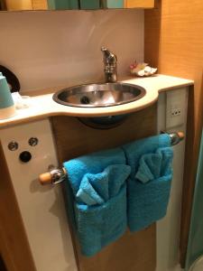 a bathroom sink with towels under a sink at Catamaran Apetahi in Uturoa