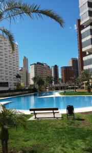 a park bench sitting next to a large swimming pool at Apartment Carmentxu Gemelos 26 in Benidorm