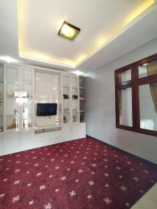 sala de estar con TV y alfombra roja en Hotel Asri Baru en Purwokerto