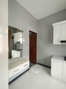 a kitchen with white cabinets and a brown door at Hotel Asri Baru in Purwokerto