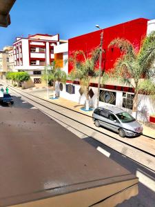 a car parked on a street next to a red building at moderno apartamento en el centro , a 3 min del mar I in Asilah