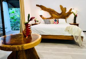 a bedroom with a bed and a tree stump table at ECOTICA Boutique Hotel in Manuel Antonio