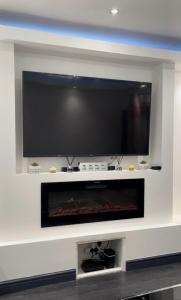 a large flat screen tv on a wall with a fireplace at Luxury Holiday Home in Manchester