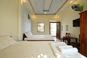 a hotel room with two beds and a television at ALOHA HOTEL SUỐI MÂY PHÚ QUỐC in Phu Quoc