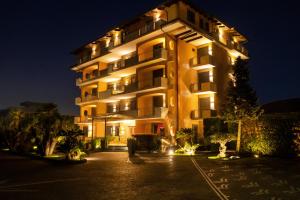 un grand bâtiment avec des lumières allumées la nuit dans l'établissement Hotel Orizzonte, à Giugliano in Campania