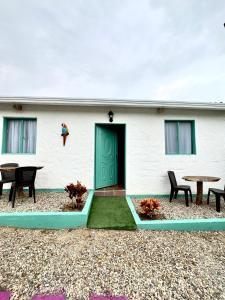 a white building with a green door and tables at Hotel La Reserva in San Gil