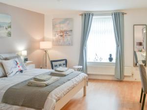 a bedroom with a bed with blue curtains and a window at Scotswood in Amble