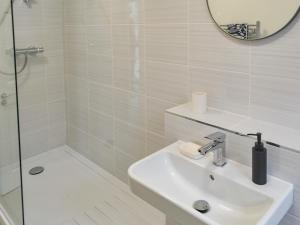 a white bathroom with a sink and a shower at Scotswood in Amble