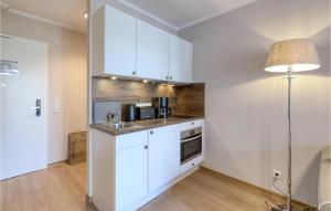 a kitchen with white cabinets and a sink and a lamp at Baltischer Hof Apartment 36 in Boltenhagen