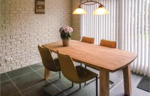 a wooden table with chairs and a vase of flowers on it at Two-Bedroom Holiday Home In Callantsoog in Callantsoog