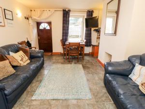 a living room with a leather couch and a table at Hunter Cottage in Haltwhistle