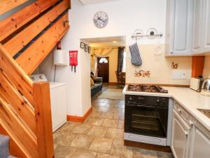 a kitchen with a stove top oven next to a staircase at Hunter Cottage in Haltwhistle