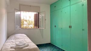 1 dormitorio con armarios verdes, 1 cama y ventana en Departamento del Parque en San Salvador de Jujuy