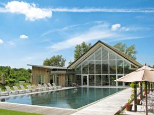 a swimming pool with chairs and a house at Muntjac Lodge in Somerford Keynes
