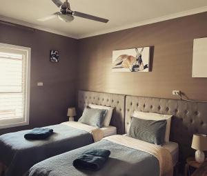1 dormitorio con 2 camas y un gato en la pared en KI Dragonfly Guesthouse, en Kingscote