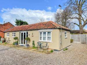 a small yellow house with a table and chairs at The Olde Stables in Lowestoft