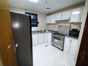 cocina con armarios blancos y nevera en Luxury 3 BHK family vacation home, en Dubái