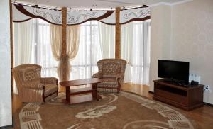 a living room with a tv and chairs and a table at Hotel&Restaurant SENATOR in Truskavets