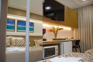 een hotelkamer met een bed en een bureau met een televisie bij FLAT PONTA NEGRA BEACH-Natal in Natal