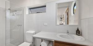 a white bathroom with a sink and a toilet at Salt Box Hideaway in Strahan