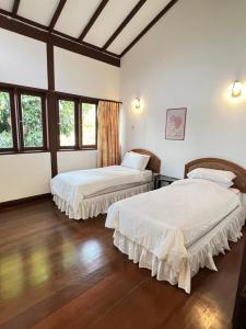 2 letti in una camera con pavimenti e finestre in legno di Honlim villa homestay a Port Dickson