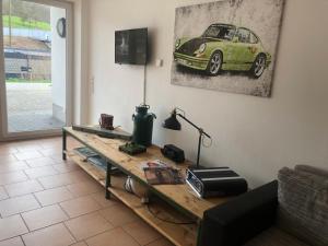 NringRooms Exit-Breidscheid في آدناو: غرفة معيشة مع طاولة مع سيارة خضراء على الحائط