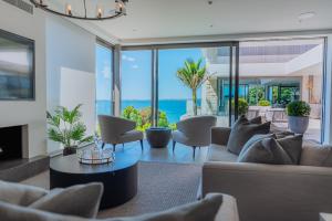 a living room with a couch and chairs and the ocean at Elements of Castor Bay in Auckland