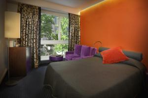 a bedroom with a bed and a purple chair and a window at The New Midi in Geneva