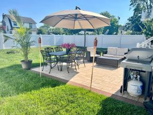 a patio with a table and an umbrella and a grill at New Beach house - 3 Blocks to the beach!! in Long Branch
