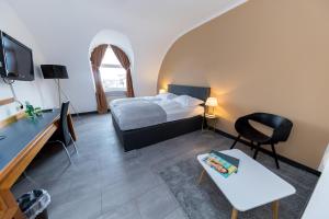 ein Schlafzimmer mit einem Bett, einem Schreibtisch und einem Fernseher in der Unterkunft Skycity Hotel Atrigon in Klagenfurt am Wörthersee