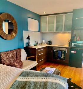 cocina con paredes azules, cama y sofá en Salt Box Hideaway, en Strahan