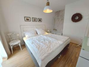 a bedroom with a white bed and a chair at Apartment in Bad Mitterndorf - Steiermark 41629 in Bad Mitterndorf