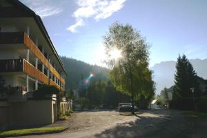 eine Straße mit einem Gebäude, einem Baum und der Sonne in der Unterkunft Apartments in Bad Mitterndorf - Steiermark 41123 in Bad Mitterndorf
