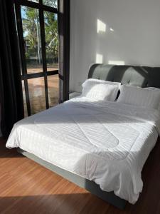 een bed met witte lakens en kussens in een slaapkamer bij A’Casa Cottage in Kuala Terengganu
