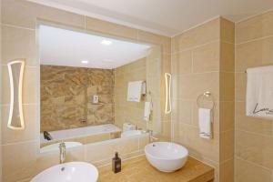 a bathroom with two sinks and a bath tub at Luau Beach Inn, Maldives in Fulidhoo