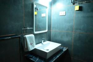 a bathroom with a sink and a mirror at Sunshine International Boarding & Lodging in Belūr +36 photos