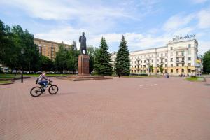 una mujer montando una bicicleta delante de una estatua en Vip-kvartira Kuzmy Chornogo 4, en Minsk