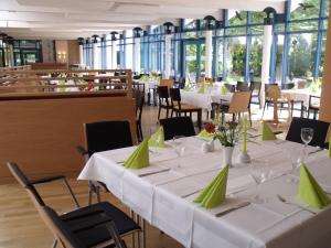 a dining room with white tables and green napkins at Hotel Ostseeländer in Züssow