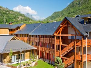a resort building with a mountain in the background at Résidence Vacancéole Les Chalets d'Ax in Ax-les-Thermes