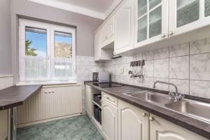 a kitchen with white cabinets and a sink at Holiday home in Balatonmariafürdo 40848 in Balatonmáriafürdő +5 photos