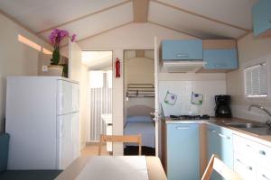 a small kitchen with a white refrigerator and a table at Mobilehomes in Pieve Vecchia - Norditalienische Seen 22044 in Manerba del Garda