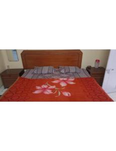 a bed with a red bedspread with flowers on it at Hotel Westend, Mussoorie in Mussoorie