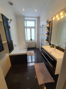 ein Badezimmer mit einer Badewanne, einem Waschbecken und einem Spiegel in der Unterkunft Apartments-in-vienna in Wien