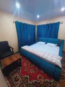a bedroom with a blue bed and a chair at Home Sweet Home in Srinagar